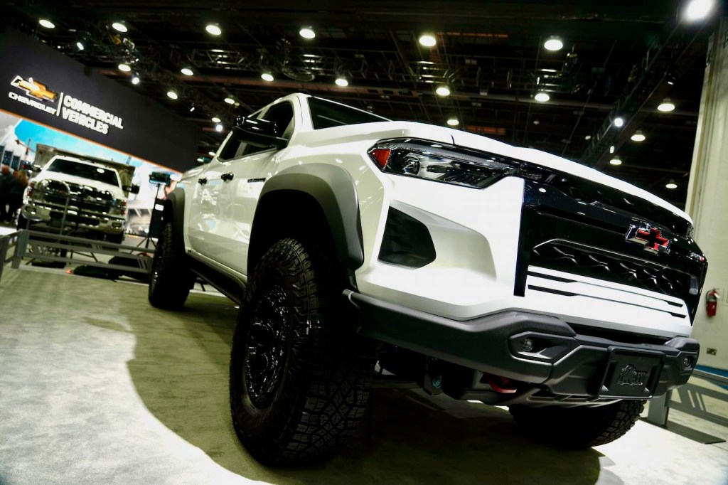 Grille of a white 2024 Chevrolet Colorado ZR2 AEV Bison pickup truck parked at an indoor car show.