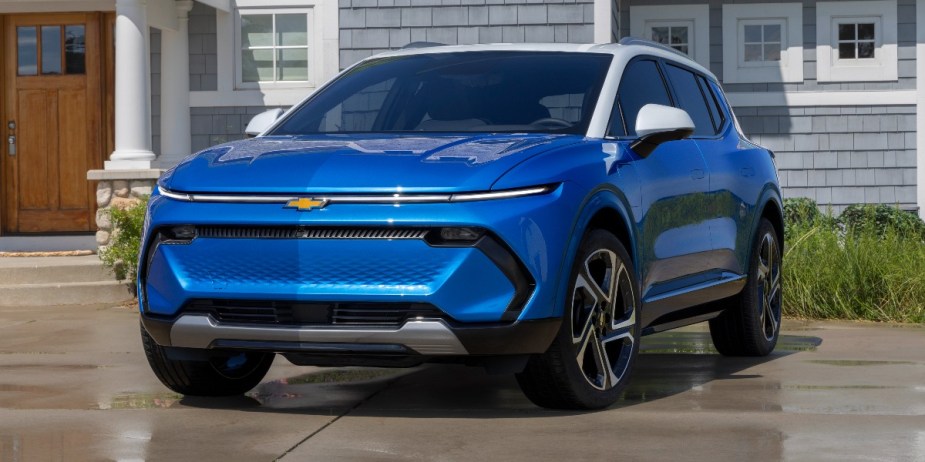 A blue 2024 Chevrolet Equinox EV electric SUV is parked in a driveway. 