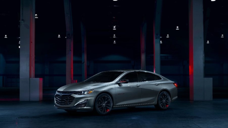 A gray 2024 Chevrolet Malibu, which shares styling with the 2023 model, sits in a dark garage.