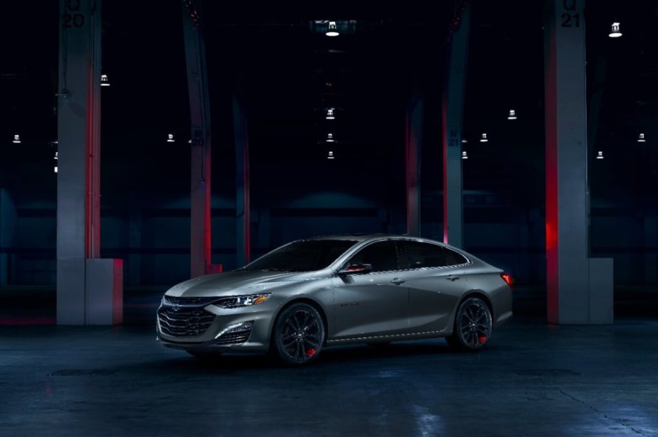A gray 2024 Chevrolet Malibu, which shares styling with the 2023 model, sits in a dark garage.