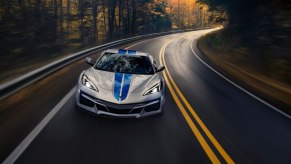 A silver and blue fully loaded 2024 Chevrolet Corvette E-Ray cruises around a corner.