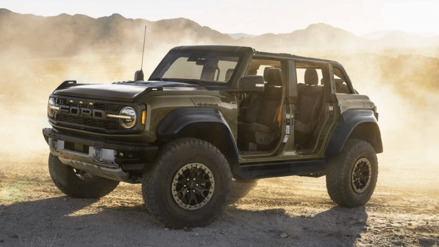 A 2024 Ford Bronco Raptor compact off-road SUV model with removable doors and all-terrain tires in a dust storm