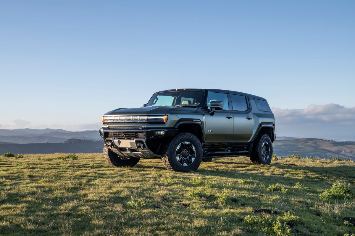 The 2024 GMC Hummer EV SUV all-electric full-size SUV model in Moonshot Green Matte parked on grass