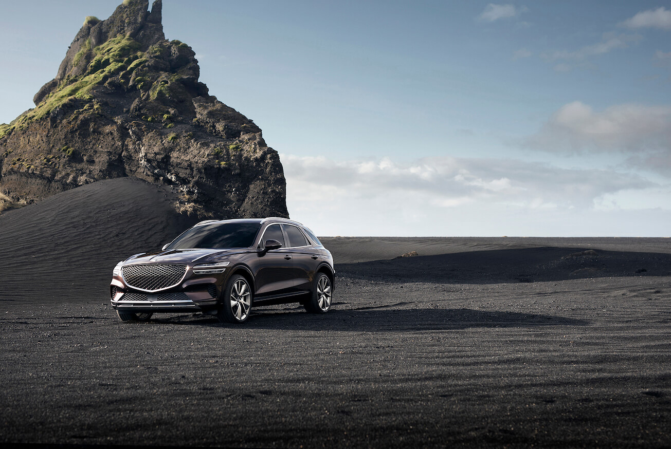 2024 Genesis GV70 in black along a rocky shore. The 2024 Genesis GV70's safety features set it apart.