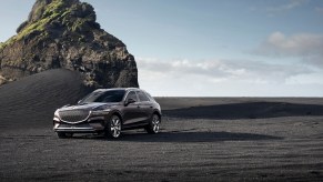 2024 Genesis GV70 in black along a rocky shore. The 2024 Genesis GV70's safety features set it apart.