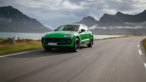 A green 2024 Porsche Macan driving down a scenic road.