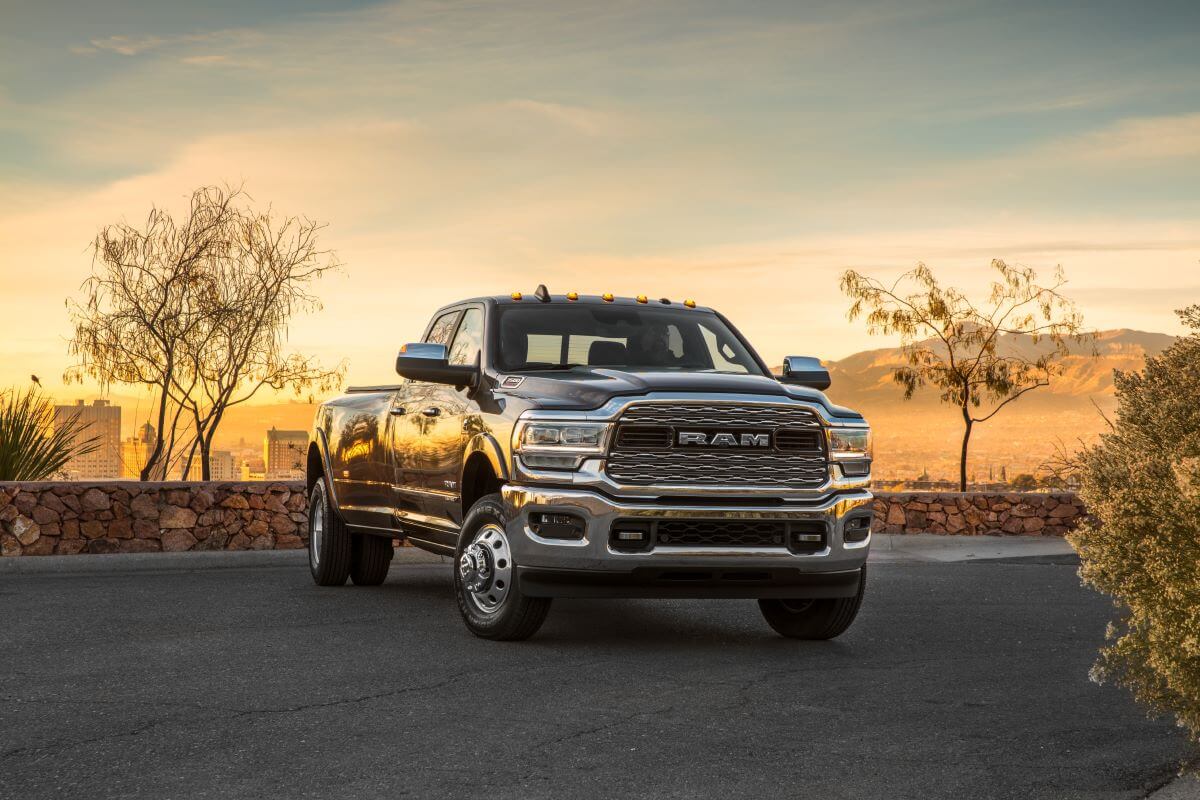 A 2024 Ram 3500 Limited Crew Cab heavy-duty pickup truck model parked by a stone ledge as the sun sets