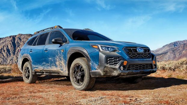 A blue 2024 Subaru Outback Wilderness midsize off-road SUV is driving off-road.