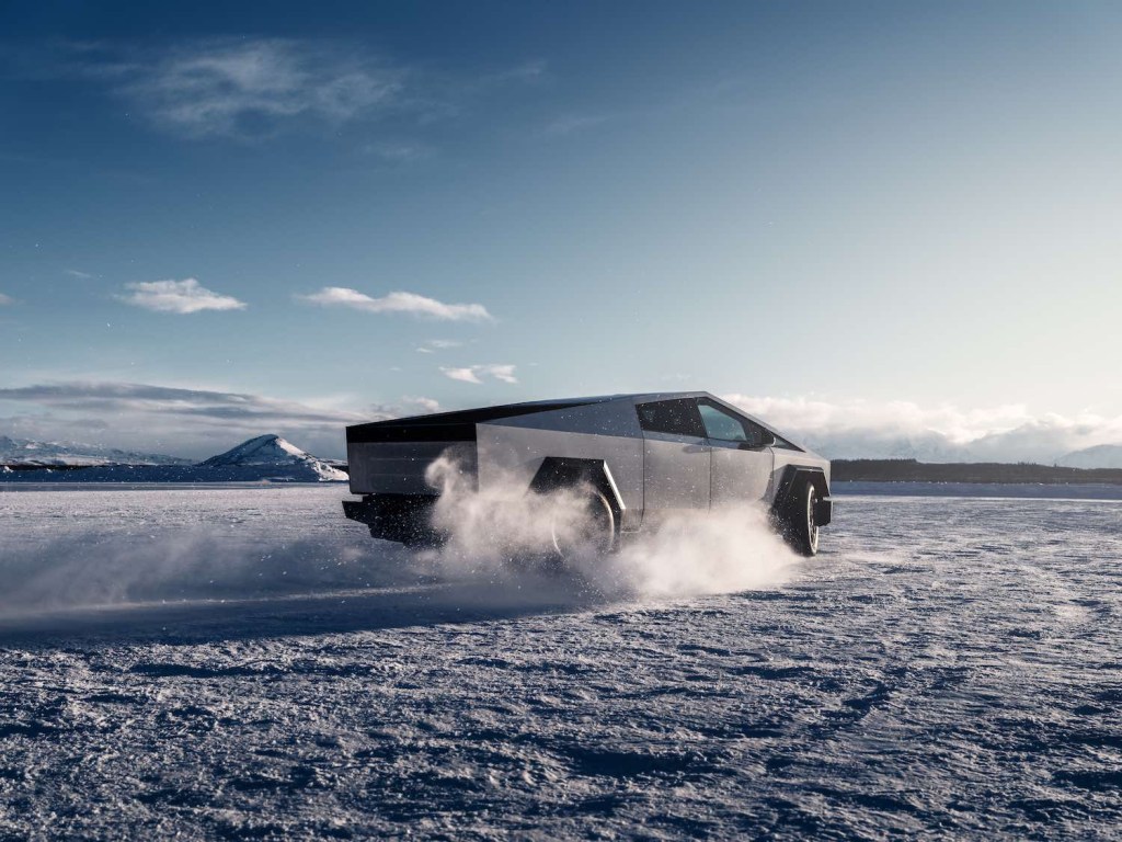 Tesla Cybertruck aggressively off-roading in the desert, clouds of sand flying off its tires.