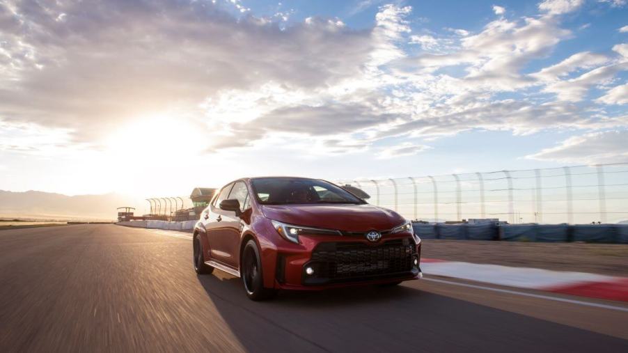 A 2024 Toyota GR Corolla performance hatchback model in Supersonic Red driving on a racetrack