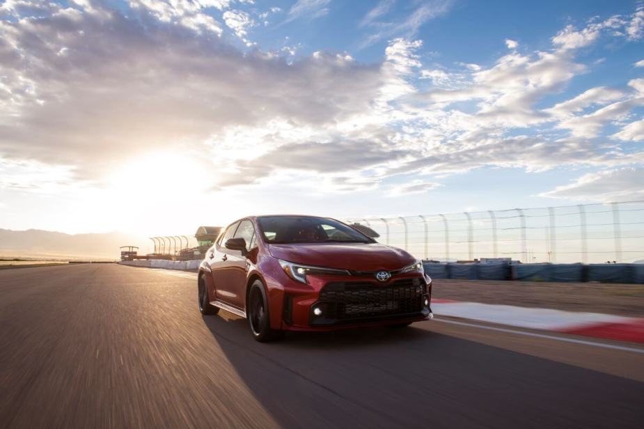 A 2024 Toyota GR Corolla performance hatchback model in Supersonic Red driving on a racetrack