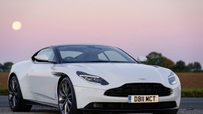 A white Aston Martin DB11, like Nathan Shelley's in 'Ted Lasso,' sits under a sunset.
