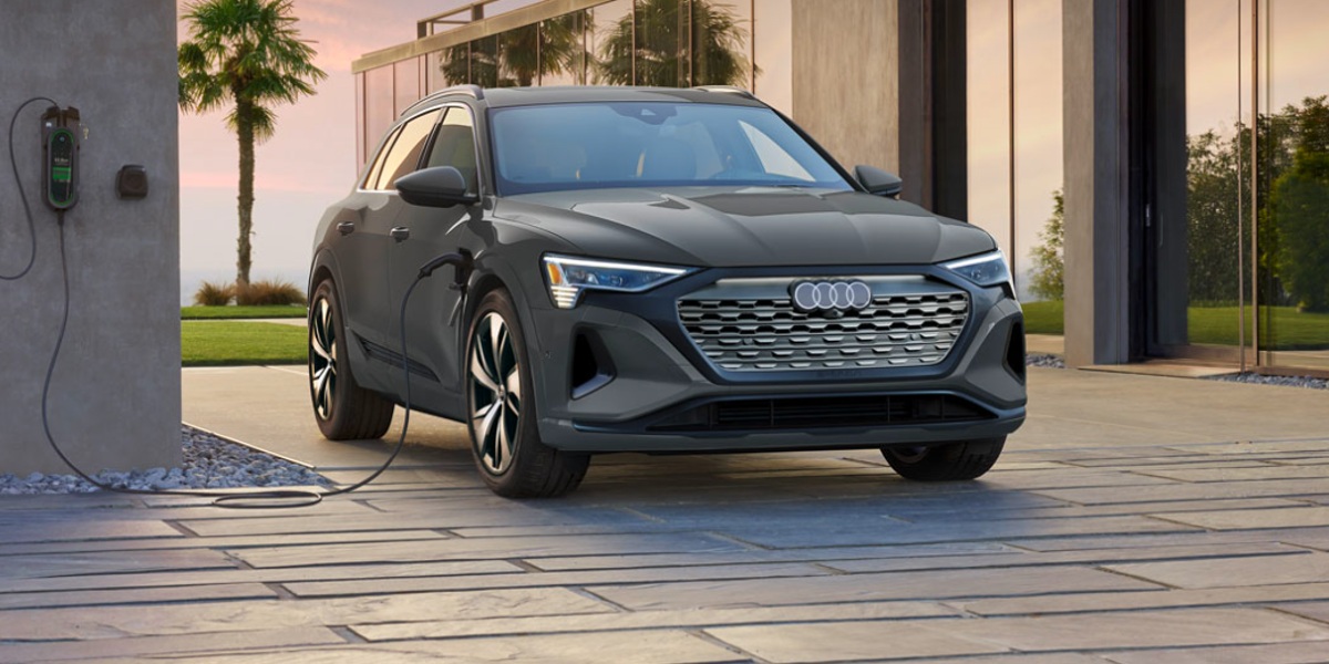 A gray Audi e-tron luxury electric midsize SUV is charging.
