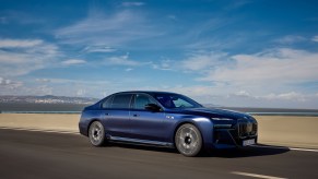 A blue BMW 7 Series driving down a desert road with blue skies. BMW 7 Series resale value is on the lower end.