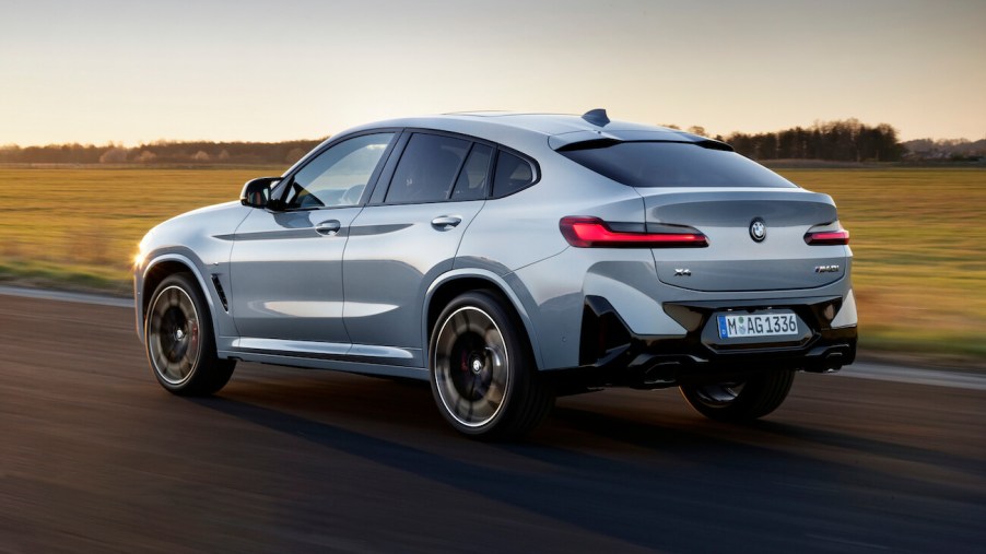 The BMW X4, the most satisfying compact luxury SUV, in gray driving down an empty road.