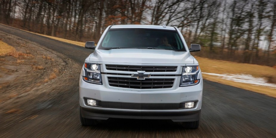 A white 2018 Chevrolet Tahoe full-size SUV is driving on the road. 