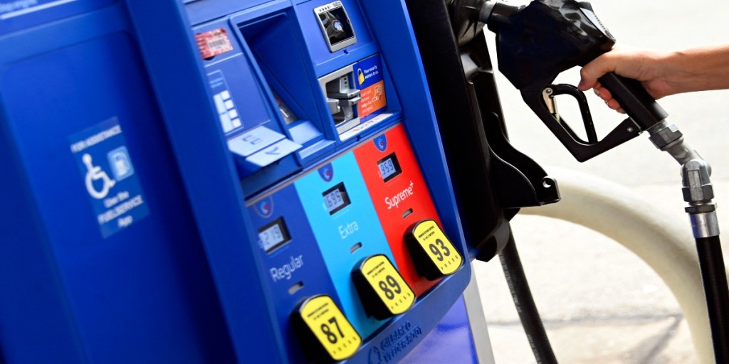 A person removes the nozel from a pump at a gas station on July 29, 2022 in Arlington, Virginia.