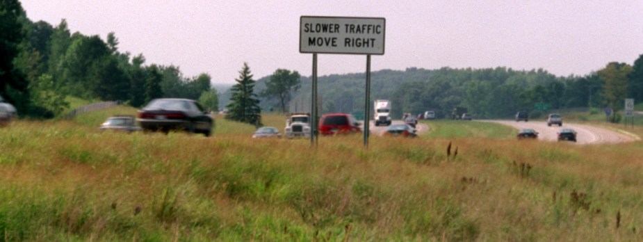 "Slower cars move right" sign posted in grass