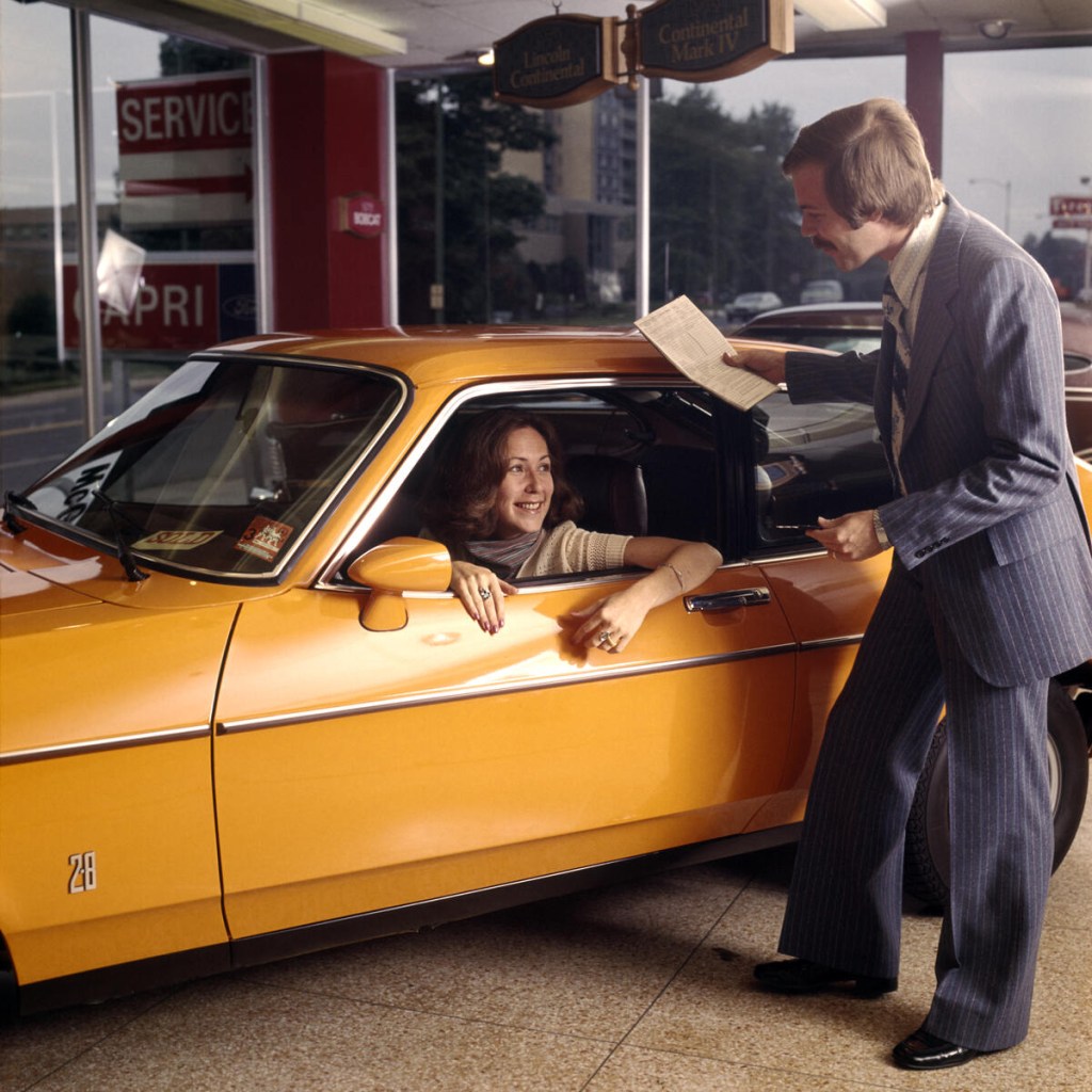 Inside a dealership with car, woman, and salesman
