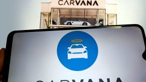 Carvana tower with a phone screen displaying Carvana logo below it.