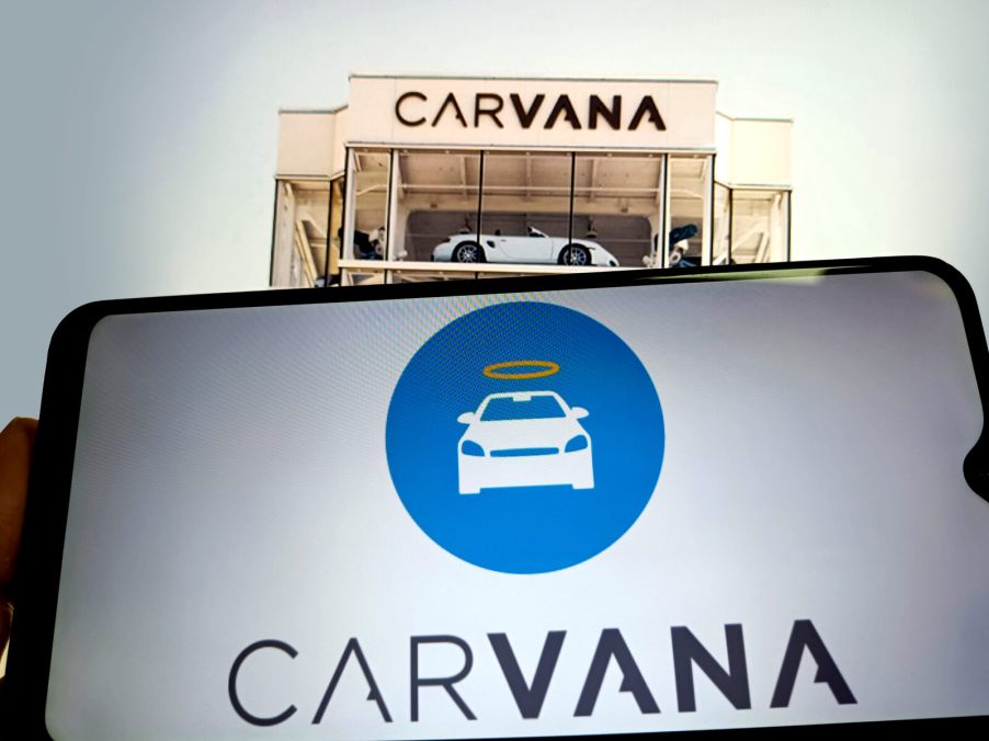 Carvana tower with a phone screen displaying Carvana logo below it.