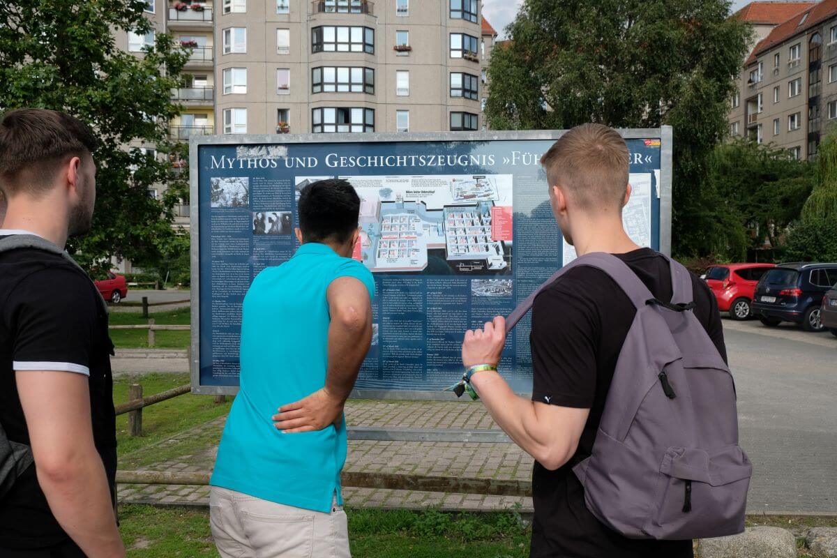 Tourists in Berlin, Germany, reading an information board about Adolf Hitler's hidden bunker and gravesite