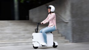A person riding on a Honda Motocompacto electric scooter.