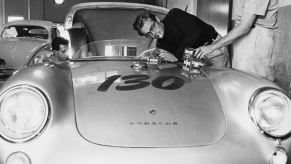 James Dean leans over his Porsche 550 while smoking a cigarette and working on the engine.