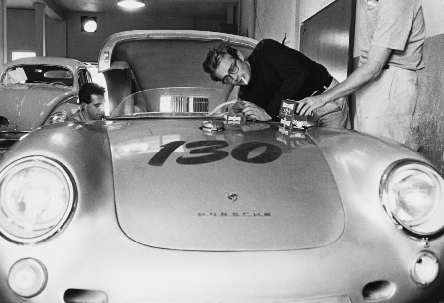James Dean leans over his Porsche 550 while smoking a cigarette and working on the engine.