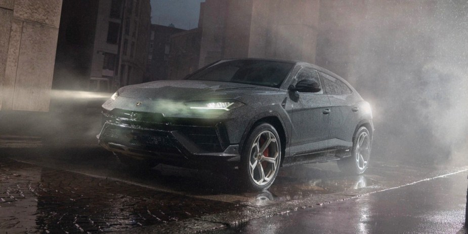 A gray Lamborghini Urus performance SUV is parked in the rain. 