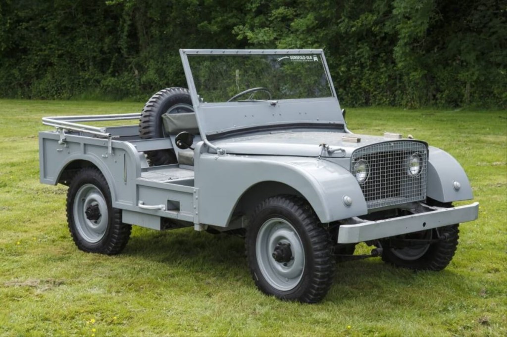 A replica of a Land Rover concept from the 1940s awaits its owner on a grassy lawn. 