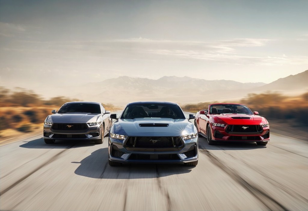 A set of 2024 Ford Mustang EcoBoost and GT Convertibles and Coupes drive on an open road. 