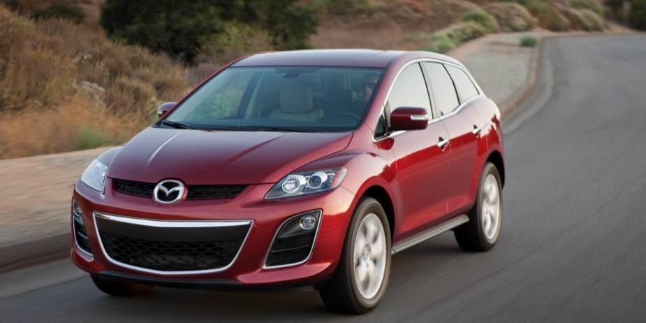 A red Mazda CX-7 midsize SUV is driving on the road.