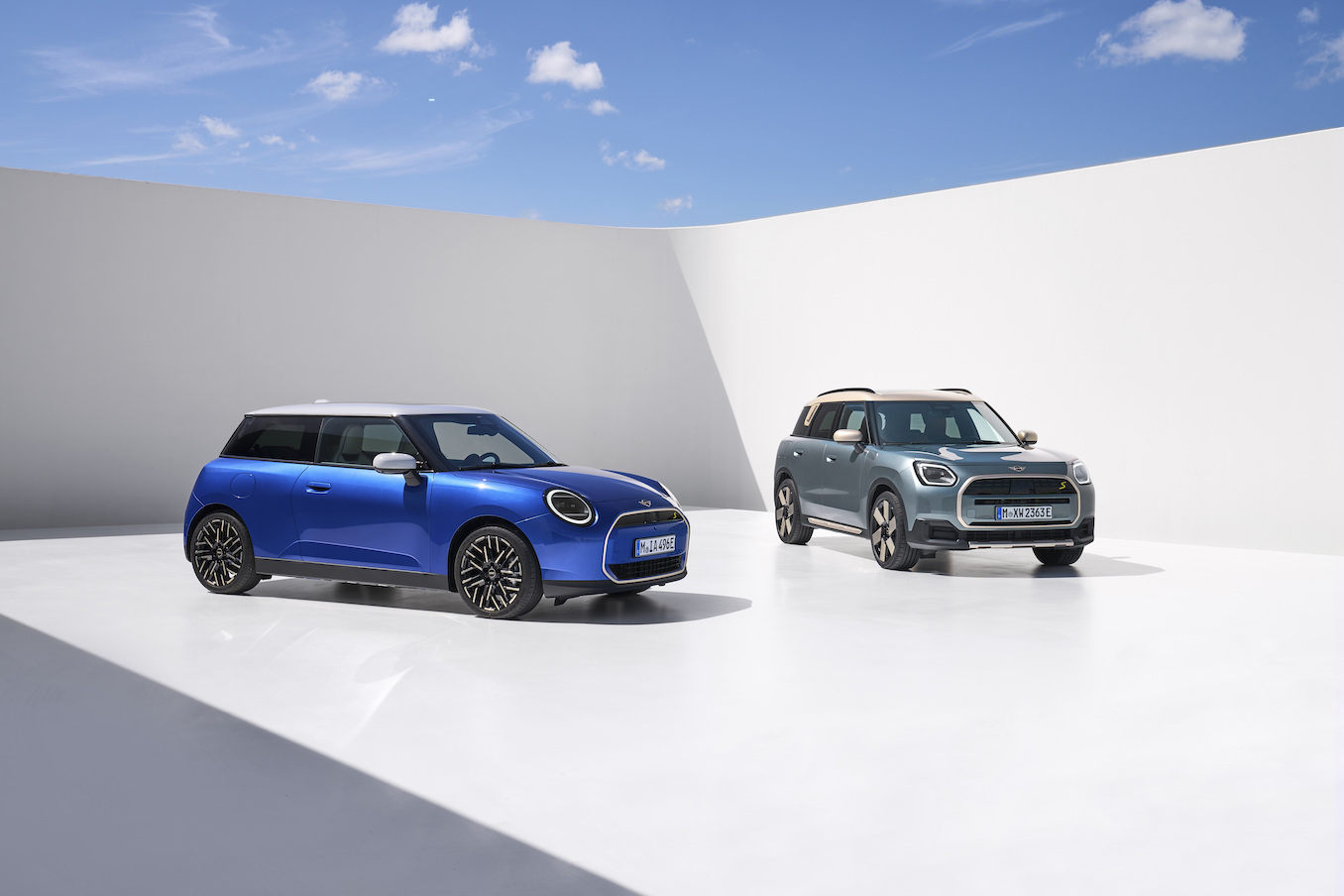 Two blue Mini Cooper models parked against a white backdrop and blue sky. This is the most dependable sports car in 2023.