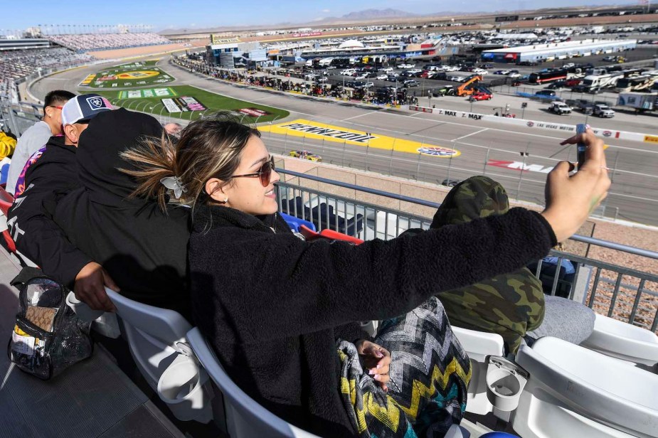 Millennial NASCAR Xfinity cup fan taking a selfie during a Las Vegas race.