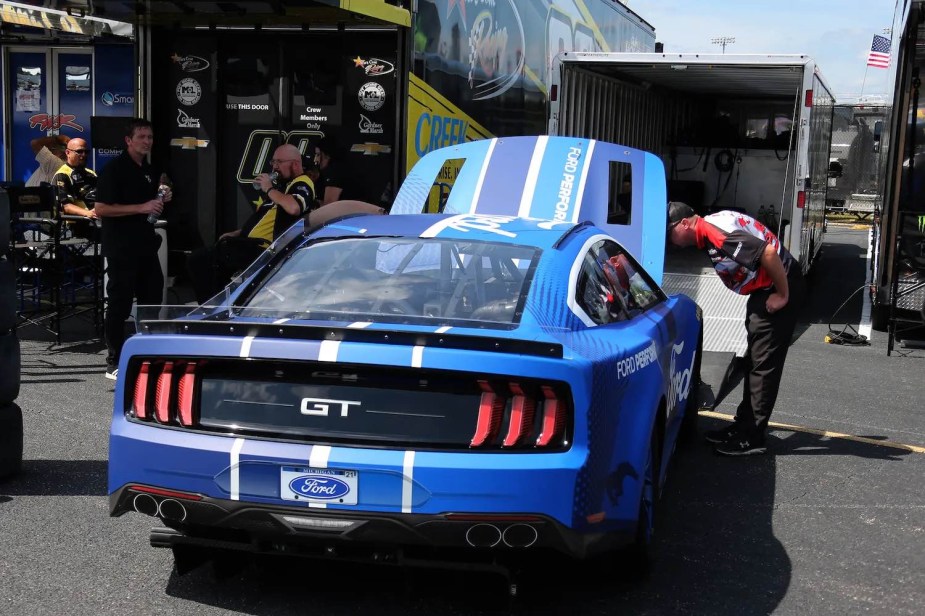 The back of a NASCAR Next Gen Ford Mustang race car with the hood of its engine bay up.