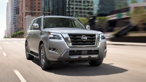A gray 2023 Nissan Armada full-size SUV is driving on the road.