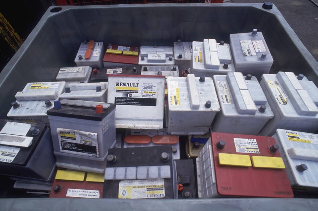 Collection of car batteries sitting in a bin ready for disposal