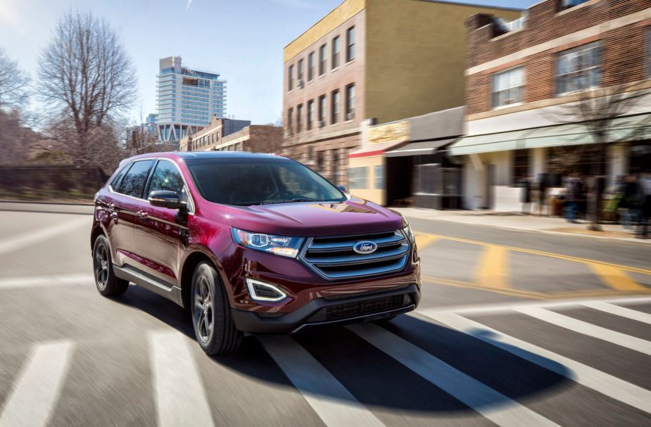 A red 2018 Ford Edge driving on a city street. This is one of the reliable Ford Edge models.