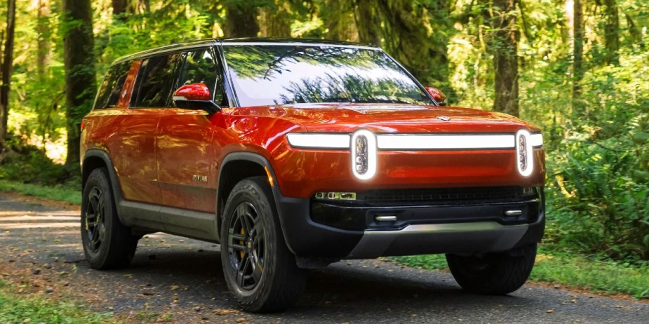 A red Rivian R1S electric SUV is parked, it's more powerful than a Ram TRX.