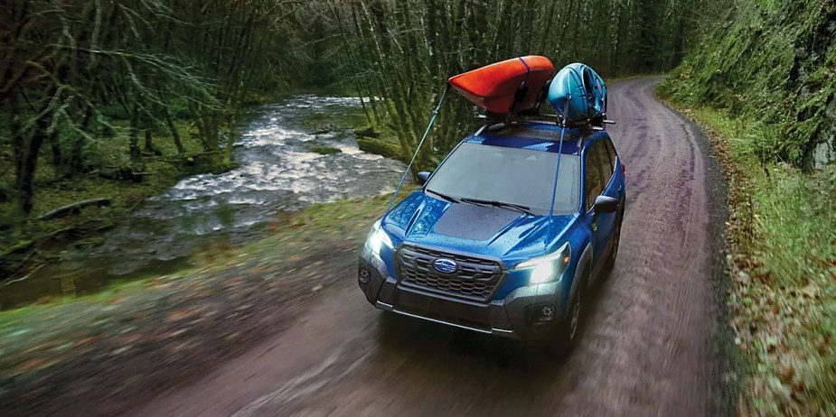 A blue Subaru Forester Wilderness small off-road SUV is driving off-road. 
