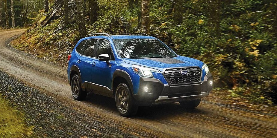 A blue Subaru Forester Wilderness small off-road SUV is driving.