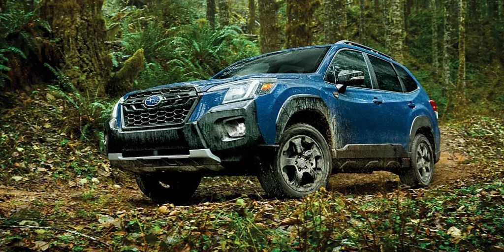 A blue Subaru Forester Wilderness small SUV is parked off-road.