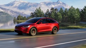 A red Tesla Model X midsize electric SUV is driving on the road.