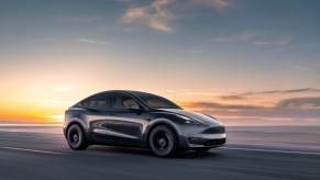A black Tesla Model Y small EV SUV is driving on the road.