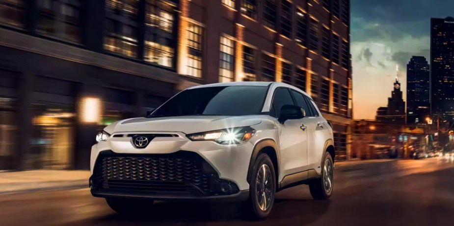 A white 2023 Toyota Corolla Cross subcompact SUV is driving.