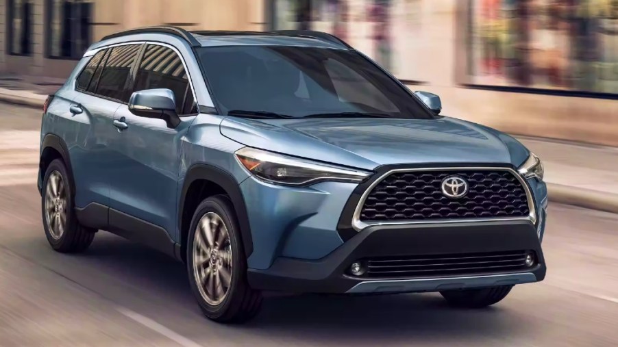 A blue Toyota Corolla Cross subcompact SUV is driving on the road.