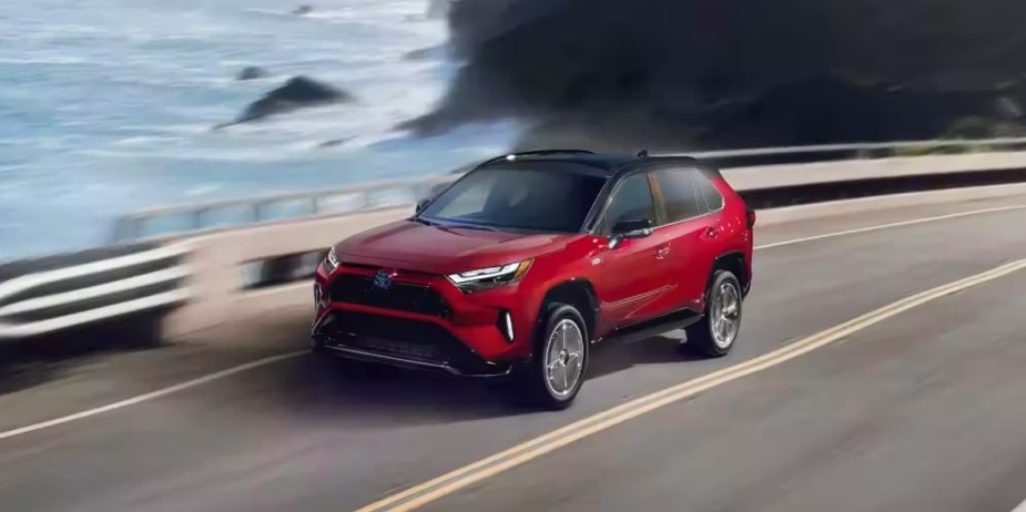 A red Toyota RAV4 Prime small plug-n hybrid SUV is driving on the road. 