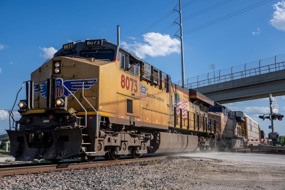 Bright yellow Union Pacific diesel locomotive on the tracks beneath a bridge.