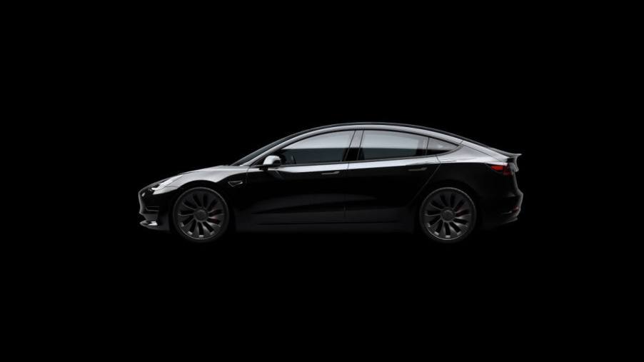 A side profile exterior shot of a Tesla Model 3 Performance all-electric compact sedan with a black background